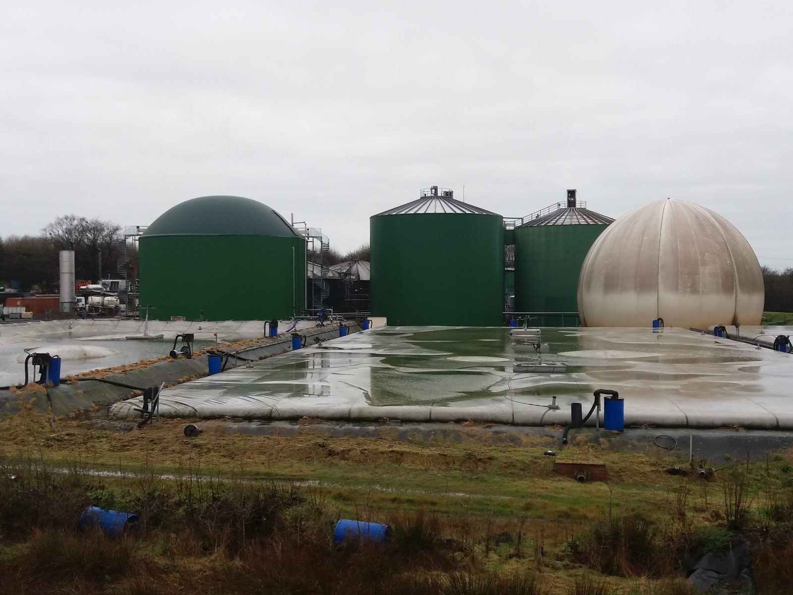 Full-scale anaerobic digestion plant with green digester tanks and a gas storage dome
